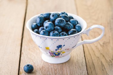 ahşap bir masa üzerinde beyaz bir vintage Kupası'nda yaban mersini