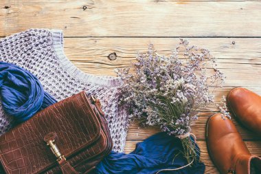 Kırmızı ayakkabılar, mor buket, kazak, eşarp ve bir antika ahşap arka plan üzerinde çanta deri kavramı