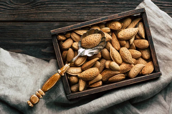 Almonds, shell nuts in a box on a wooden background, autumn still life