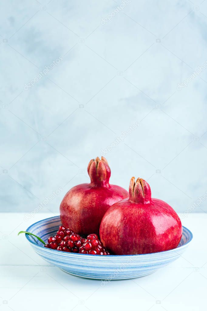 Pomegranate, three pieces, gray stone background, blue plate, southern fruit, copy place