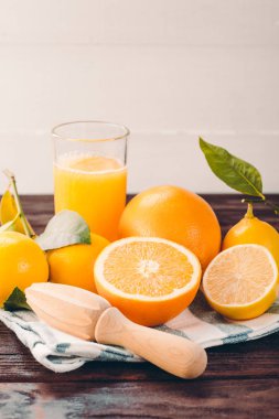 Lezzetli turuncu ve ahşap masa üzerinde meyve sıkacağı ile cam meyve suyu hazırlama