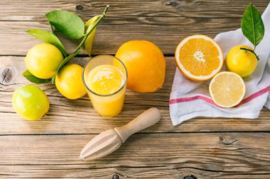 Lezzetli turuncu ve ahşap masa üzerinde meyve sıkacağı ile cam meyve suyu hazırlama