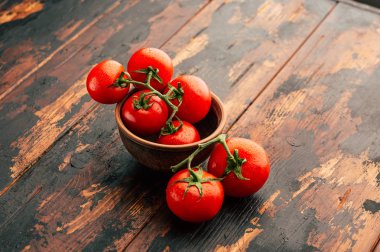 Bir şube, kil kase ve ahşap arka plan, taze sebze olgun domates