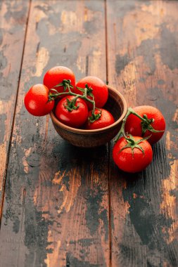 Bir şube, kil kase ve ahşap arka plan, taze sebze olgun domates