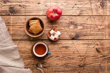 Çay, elma, kurabiye ve şeker bir kahverengi ahşap masa, Kahvaltı, rustik tarzı, Aperatif, üstten görünüm alanı Kopyala