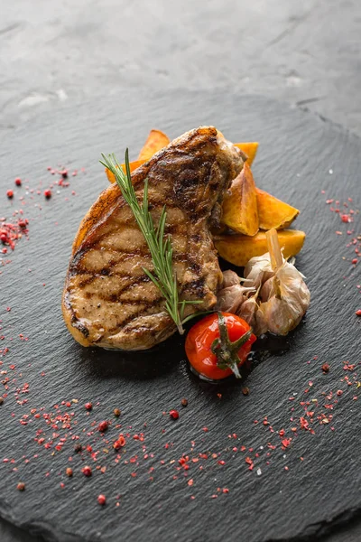 Grilled pork with potatoes, ready meal, black slate background