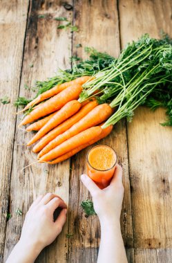 elinde taze havuç suyu bir bardak, ahşap arka plan