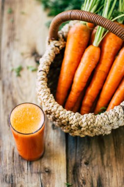 Ahşap bir arka plan, havuç suyu, sebze hasat üzerinde kök ve yaprakları ile Taze havuç