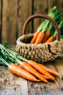 Sapı ve yaprakları ile taze havuç ahşap bir masa, sebze bir ürün üzerinde bir sepet içinde