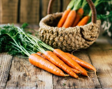 Sapı ve yaprakları ile taze havuç ahşap bir masa, sebze bir ürün üzerinde bir sepet içinde