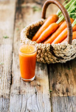 Ahşap bir arka plan, havuç suyu, sebze hasat üzerinde kök ve yaprakları ile Taze havuç
