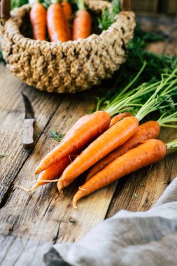Tahta bir masada saplı taze havuç ve yapraklar, sebze mahsulü