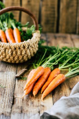 Tahta bir masada saplı taze havuç ve yapraklar, sebze mahsulü