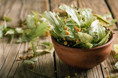 Ahşap bir masa üzerinde bir kil fincan kuru ıhlamur çiçekleri, şifalı bitkiler hasat