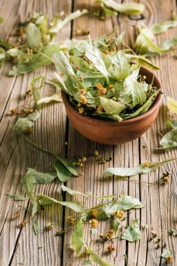 Ahşap bir masa üzerinde bir kil fincan kuru ıhlamur çiçekleri, şifalı bitkiler hasat