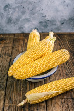Ahşap bir arka plan üzerinde koçan taze çiğ mısır
