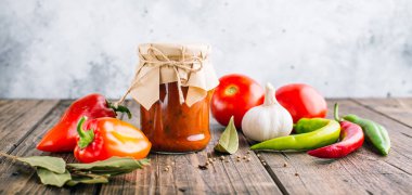 Ahşap bir arka plan üzerinde bir kavanozda Adjika, baharatlı domates sosu