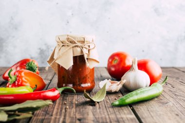 Ahşap bir arka plan üzerinde bir kavanozda Adjika, baharatlı domates sosu