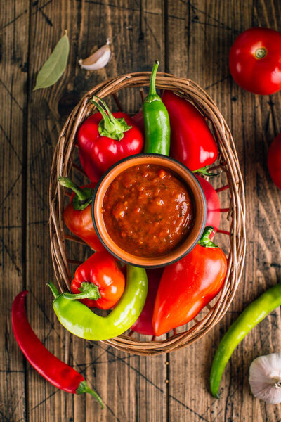 Adjika, spicy tomato sauce, vegetable snack on a wooden background