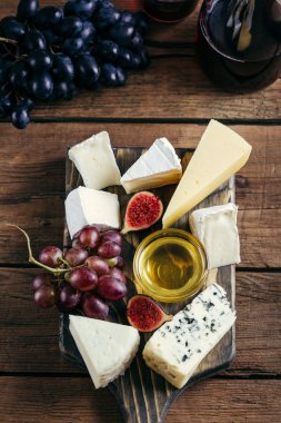 Ahşap bir arka plan üzerinde çeşitli peynir ve kırmızı şarap