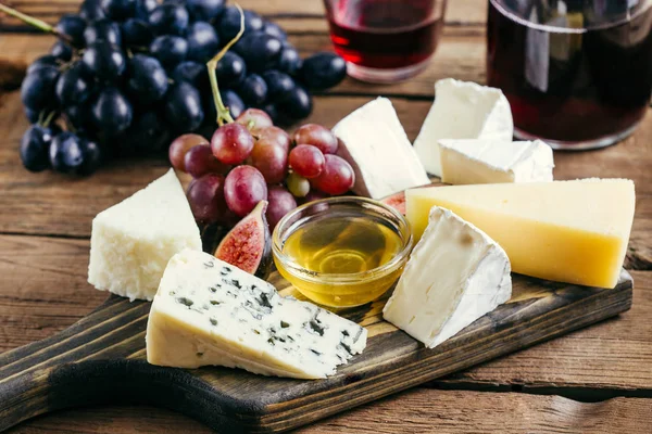 Various cheese and red wine on a wooden background