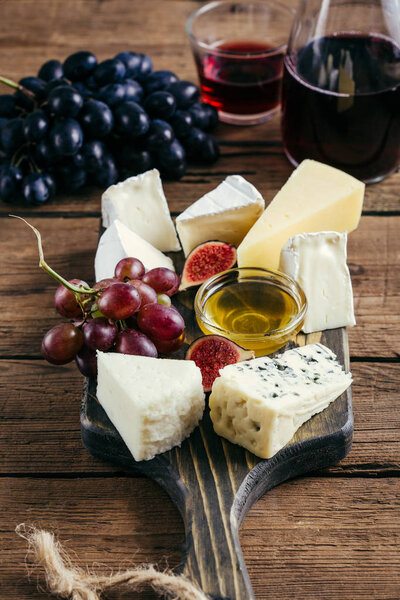 Various cheese and red wine on a wooden background
