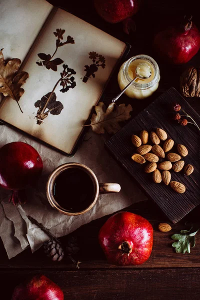 Winter concept. Old book, tea, pomegranates and nuts on a wooden table