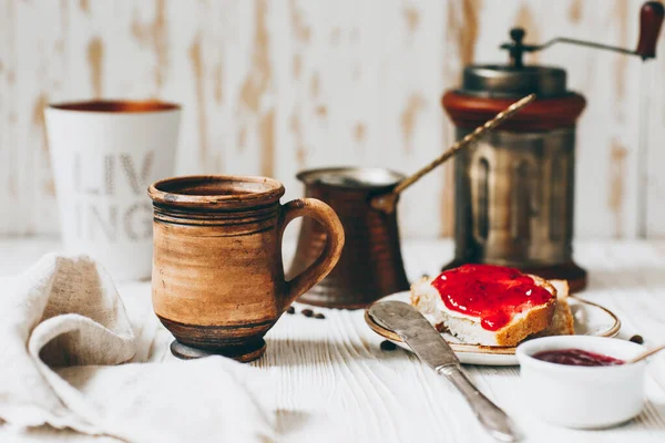 Coffee, toast and jam on a white wooden table