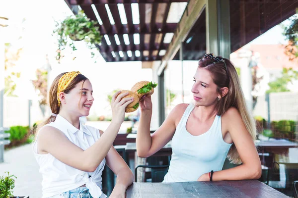 Friends eating burgers in a street cafe