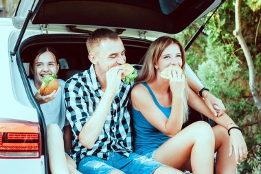 Bir grup genç bir arabanın bagajında oturuyor.