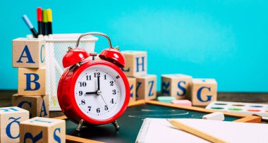 Okula dönüş kavramı. Alarm saati, tebeşir, kalem, defter, kırtasiye malzemesi, tebeşir tahtası arkaplanı. Tasarım. Boşluğu Kopyala 