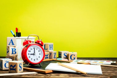 Okula dönüş kavramı. Alarm saati, tebeşir, kalem, defter, kırtasiye malzemesi, tebeşir tahtası arkaplanı. Tasarım. Boşluğu Kopyala 