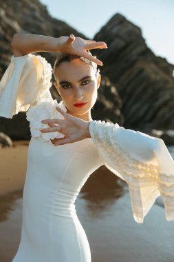 Young flamenco dancer stares at camera striking a dramatic pose at dusk
