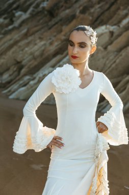 Serene flamenco dancer poses on the beach wearing elegant white attire