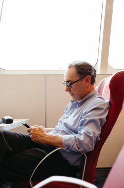 Passenger with glasses browsing phone during ferry trip