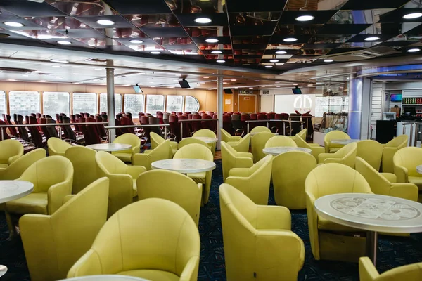 Spacious empty ferry lounge with yellow and red seats