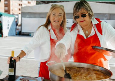 İki kadın, yerel bir sokak festivalinde tavşan yahnisi pişirmekten hoşlanıyor