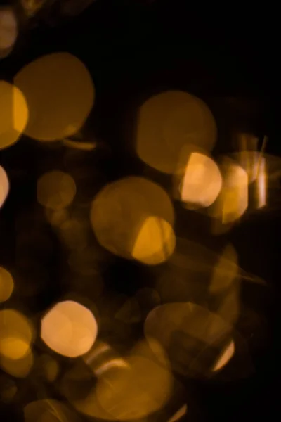 Golden bright glow bokeh. Christmas vintage lights on black background. Colorful blurred abstract defocused