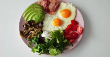 Mantarlar ve domatesler tabakta yatar ve vücudu güçlendirmek için besin içerir. Organik malzemeler yemeği süslüyor ve keto kahvaltısı atmosferi yaratıyor.
