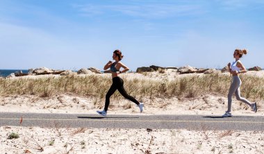 Kumsalda çalıştıran fitness kadınlar. Açık havada koşu mutlu kızlar kadın