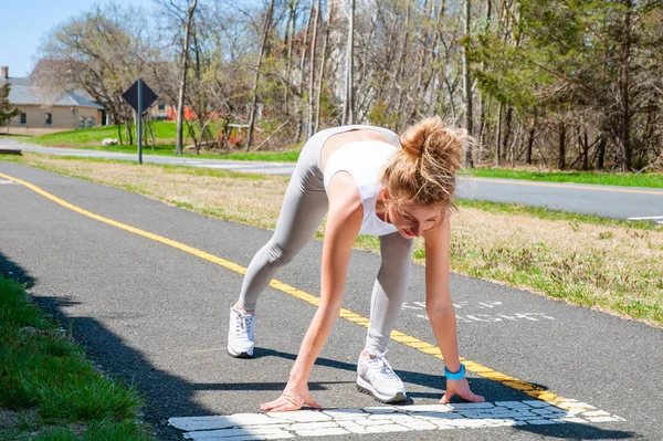 Sprinter woman getting ready to start on the running track. Female runner is waiting for the start signal