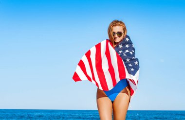 Bir Amerikan bayrağı sahilde tutan güzel neşeli kadın. Seyahat. ABD
