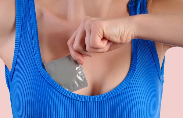 Kızın göğsünü prezervatifle tutan kadın. Güvenli seks kavramı