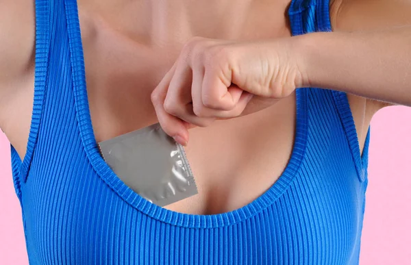 Kızın göğsünü prezervatifle tutan kadın. Güvenli seks kavramı