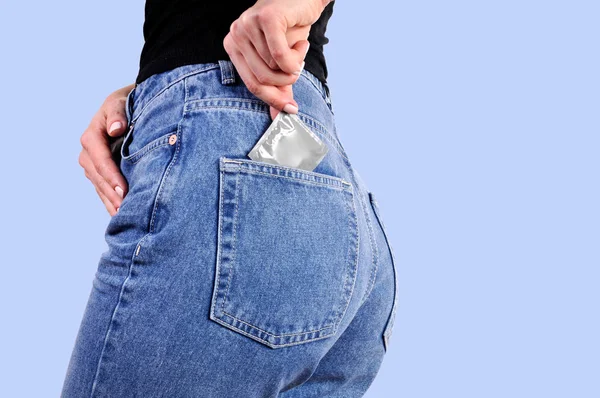 Condoms in package in back jeans pocket. Woman in jeans putting a condom a pocket.