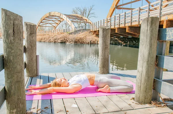 Beautiful woman practicing yoga by the lake.  Concept of calm and meditation.