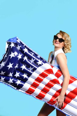 Yaz tatili. Güneş kadın bikini ile şişme yatak Amerikan bayrağı sahilde zevk.