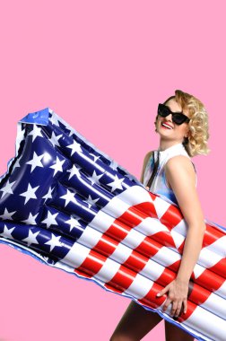 Yaz tatili. Güneş kadın bikini ile şişme yatak Amerikan bayrağı sahilde zevk.