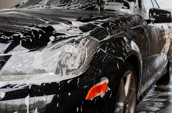 Car washing. Cleaning modern car covered by foam.