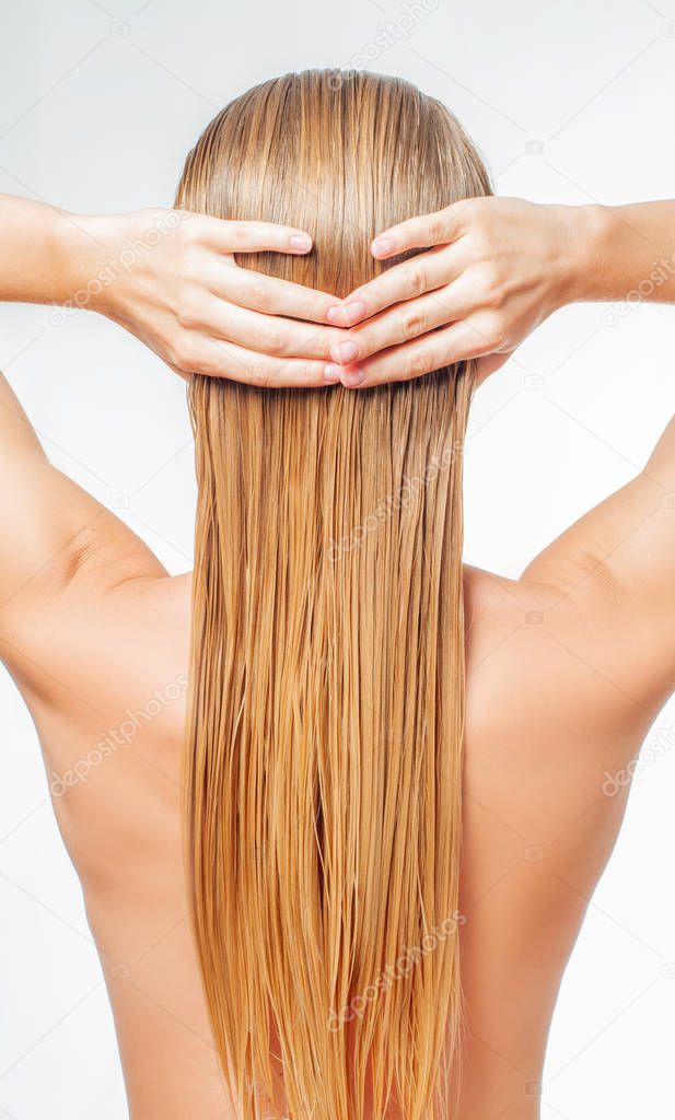 Hair care concept. Blond woman with long wet hair is applying hair conditioner